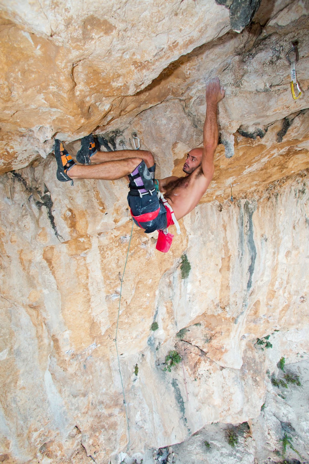 Klajmer jilħaq fuq sporġenza wieqfa tal-ġebla tal-franka oranġjo, marbut mal-quickdraws